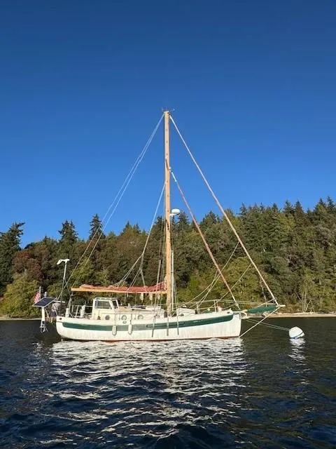 Slide: The Image of 1985 Bristol Channel Cutter 28 sailboat with solar panels and American flag, anchored near forested shoreline. - 10