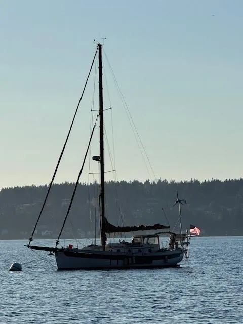 Slide: The Image of 1985 Bristol Channel Cutter 28 sailboat on calm water, forested shoreline in background. - 9