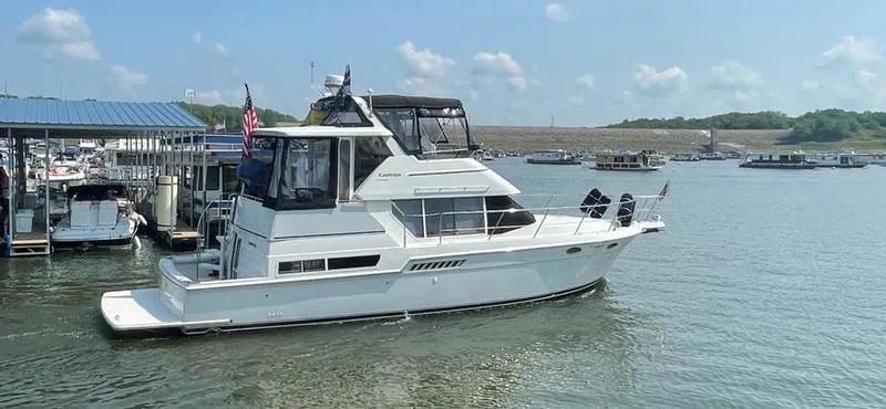 Slide: The Image of 1997 Carver 400 CPMY yacht docked on a sunny day, surrounded by calm waters. - 11