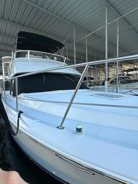 Slide: The Image of 1997 Carver 400 CPMY yacht docked in covered marina, showcasing sleek design and spacious deck. - 12