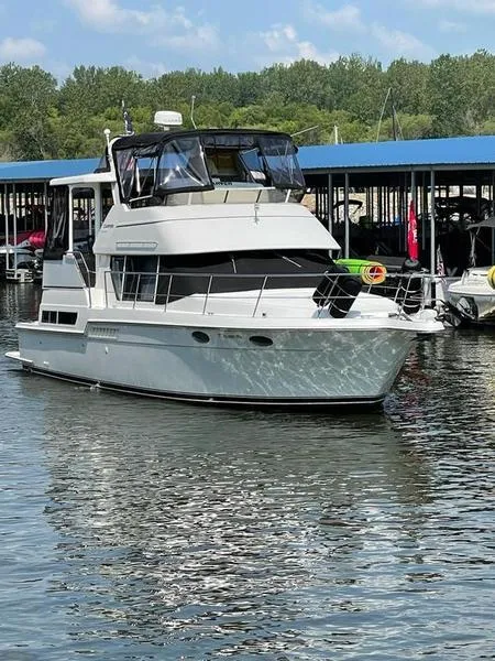 Slide: The Image of 1997 Carver 400 CPMY yacht docked on calm water, surrounded by trees and marina. - 19