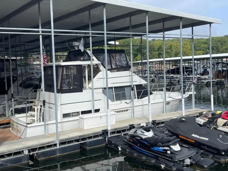 Slide: The Image of 1997 Carver 400 CPMY yacht docked in a marina with jet skis nearby. - 4