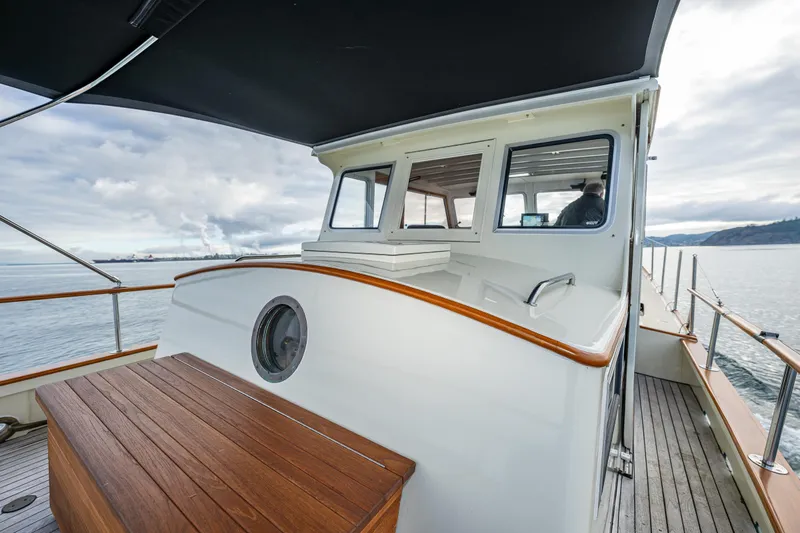 Slide: The Image of 1975 Rough Water 35 boat with wooden deck and cabin, cruising on a calm sea. - 12