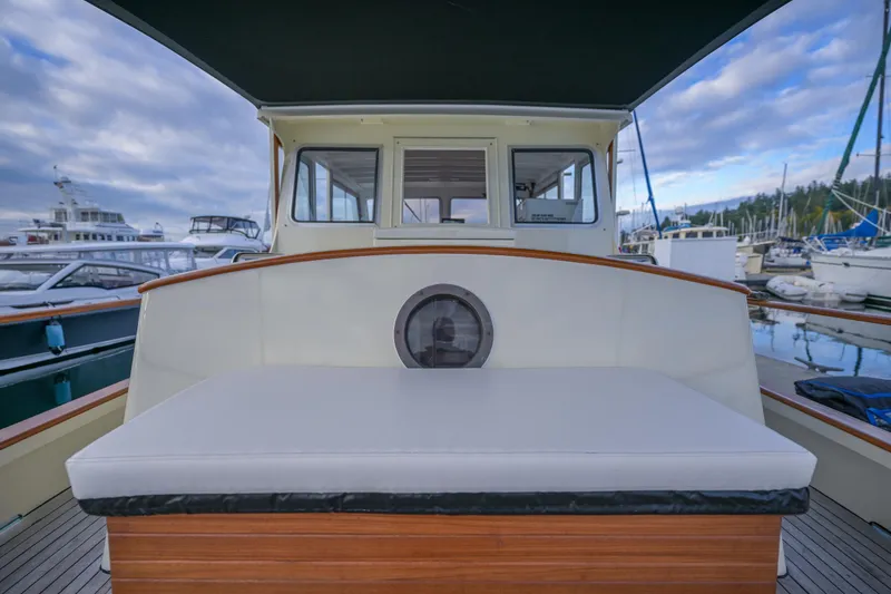 Slide: The Image of 1975 Rough Water 35 boat interior with cushioned seating, docked at a marina under cloudy skies. - 14
