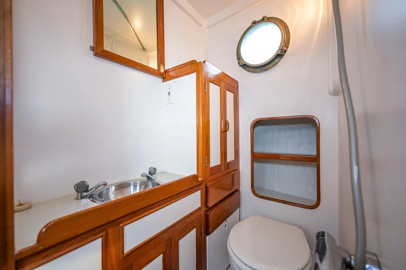 Slide: The Image of 1975 Rough Water 35 boat bathroom with wooden cabinetry and porthole window. - 27