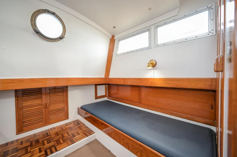 Slide: The Image of 1975 Rough Water 35 boat cabin with wooden interior, single bed, and porthole window. - 29