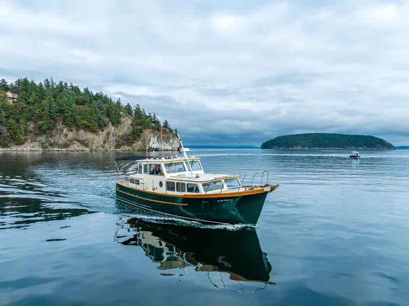 Slide: The Image of Vintage 1975 Rough Water 35 boat cruising on calm waters near forested islands. - 37