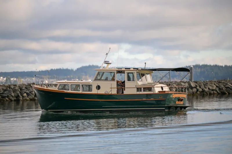 Slide: The Image of Vintage 1975 Rough Water 35 boat cruising near rocky shoreline under cloudy sky. - 38