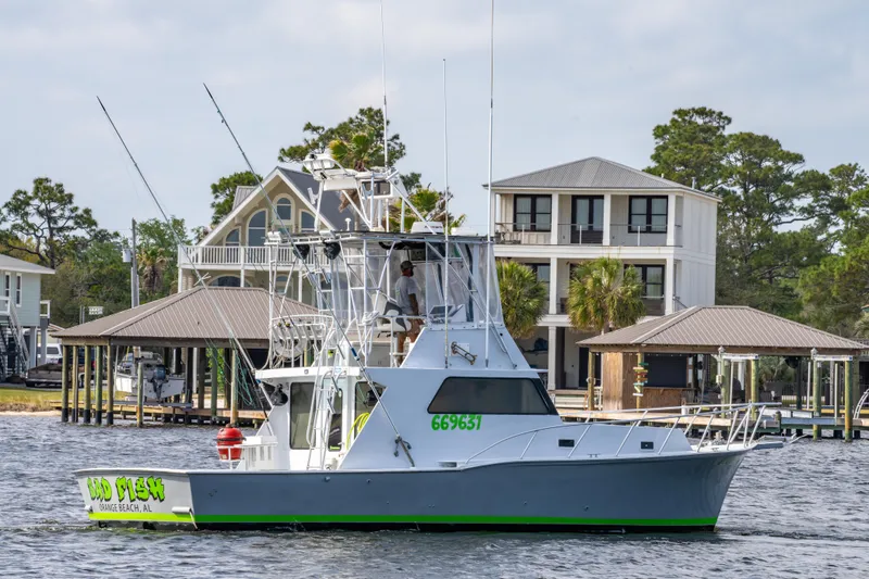 Slide: The Image of 1983 Resmondo 38 boat on water near waterfront homes, featuring fishing equipment and antennas. - 1