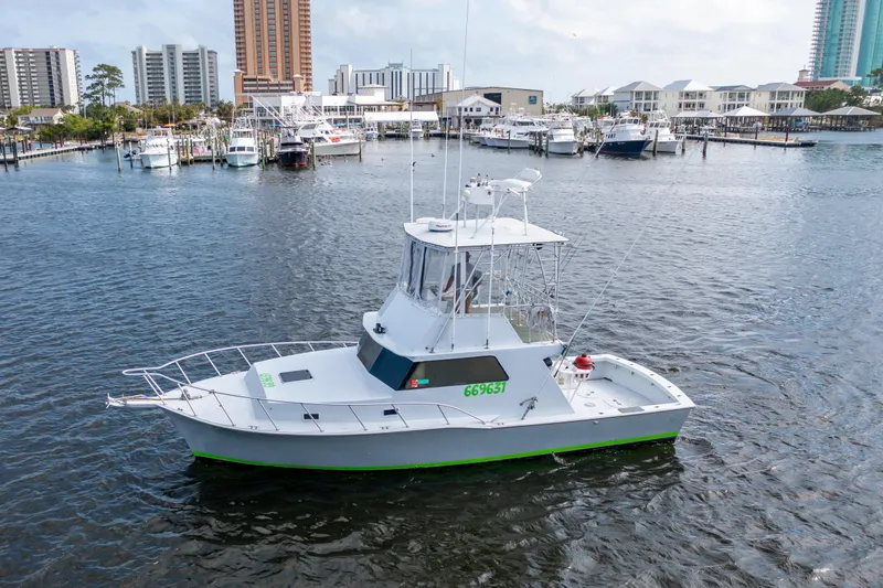 Slide: The Image of 1983 Resmondo 38 boat docked in a marina with cityscape background. - 38