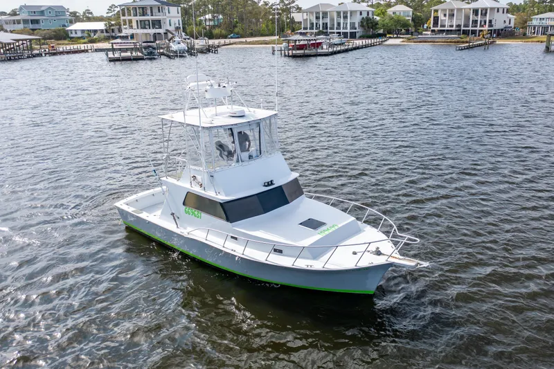 Slide: The Image of 1983 Resmondo 38 boat cruising on a calm river near waterfront homes. - 39
