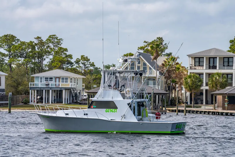 Slide: The Image of 1983 Resmondo 38 boat cruising near waterfront homes, surrounded by trees and calm water. - 6