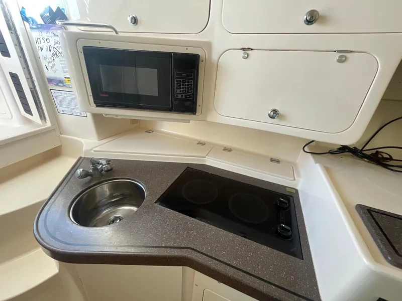 Slide: The Image of 2002 Grady-White Express 330 boat kitchen with sink, stove, and microwave. - 12