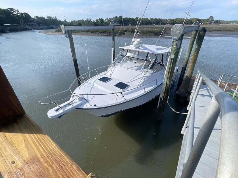 Slide: The Image of 2002 Grady-White Express 330 boat docked on a lift by the water. - 2
