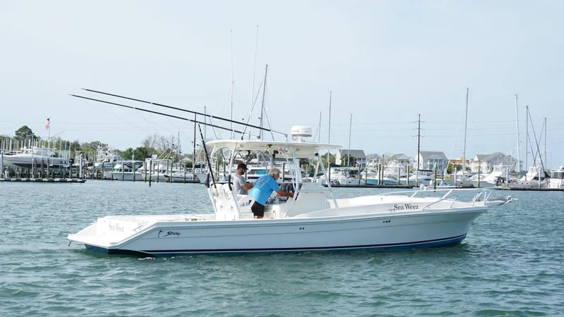 Slide: The Image of A 2016 Strike 35 boat on water near a marina, with fishing rods visible. - 2