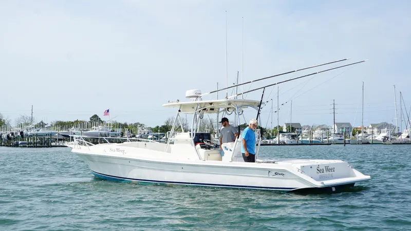 Slide: The Image of 2016 Strike 35 boat on water with two people, fishing rods, and marina background. - 5