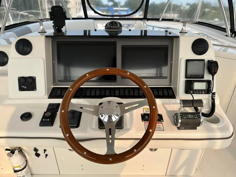 Slide: The Image of 2006 Sea Ray 58 Sedan Bridge helm with dual screens and wooden steering wheel. - 16