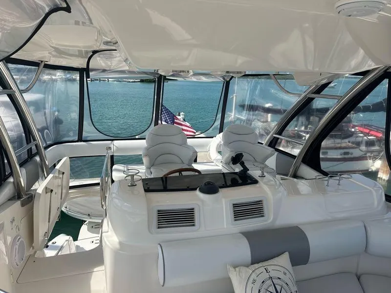 Slide: The Image of 2006 Sea Ray 58 Sedan Bridge yacht interior with helm, overlooking ocean and American flag. - 6