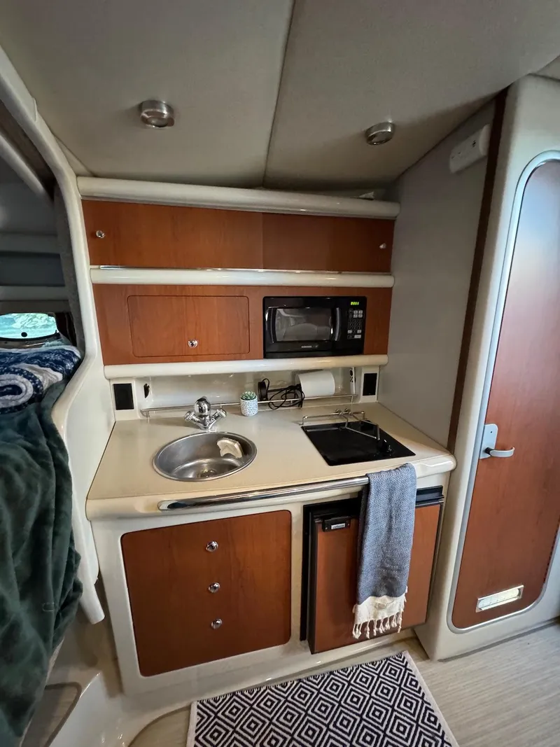 Slide: The Image of 2003 Chaparral Signature 280 cabin kitchen with sink, microwave, and stove. - 14