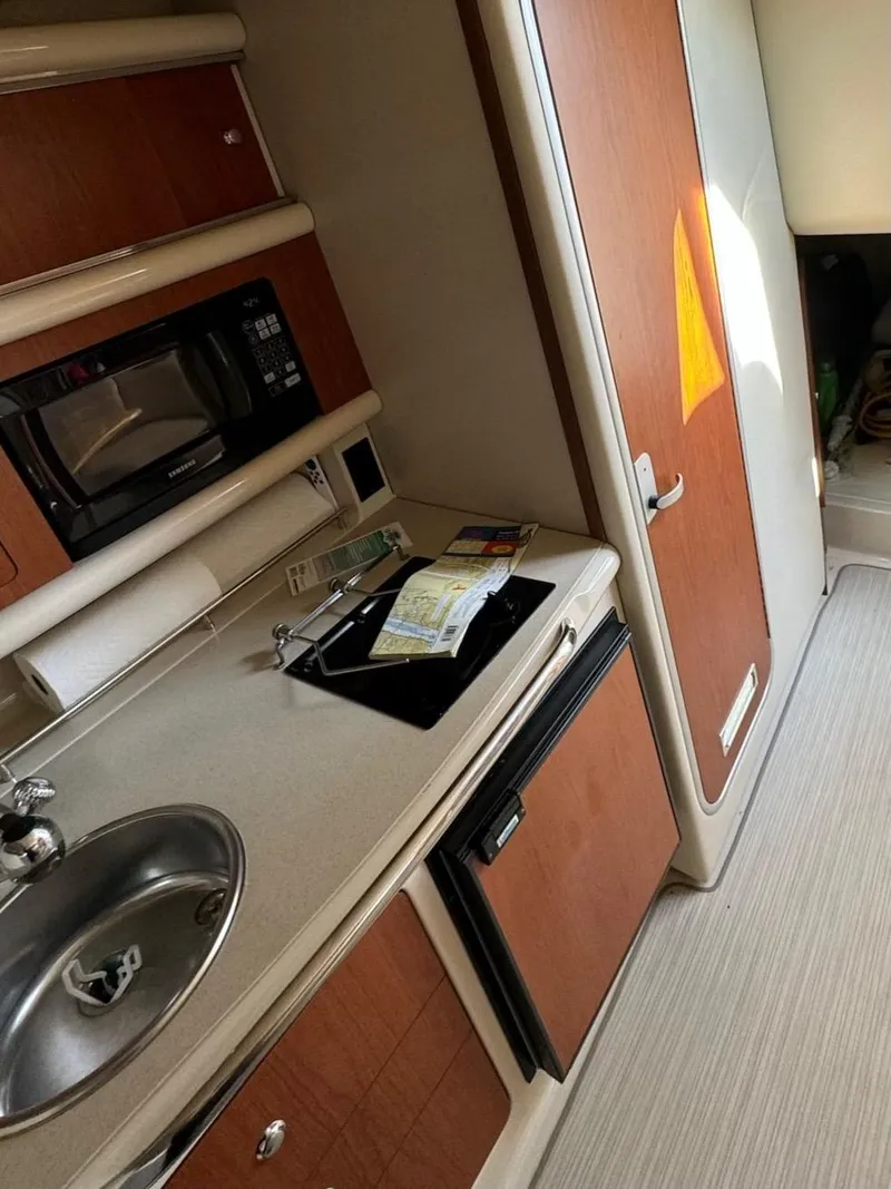 Slide: The Image of 2003 Chaparral Signature 280 cabin kitchen with sink, microwave, and compact fridge. - 21