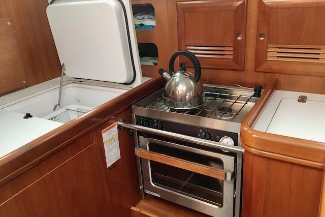 Slide: The Image of Beneteau 361 yacht kitchen with stove, kettle, and wooden cabinetry, 2001 model. - 11
