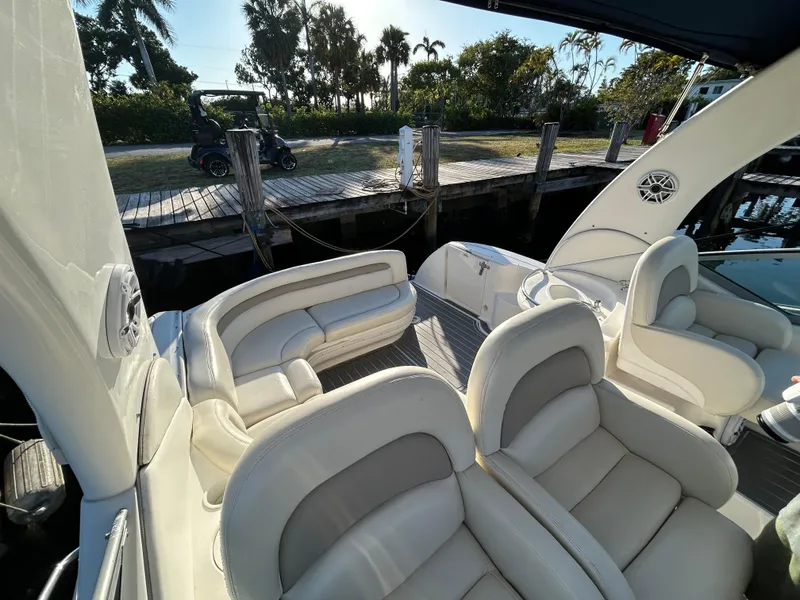 Slide: The Image of 2004 Sea Ray 340 Sundancer boat interior with plush seating, docked near a wooden pier. - 13