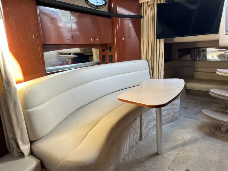 Slide: The Image of Interior of 2004 Sea Ray 340 Sundancer with curved seating and wooden cabinetry. - 20