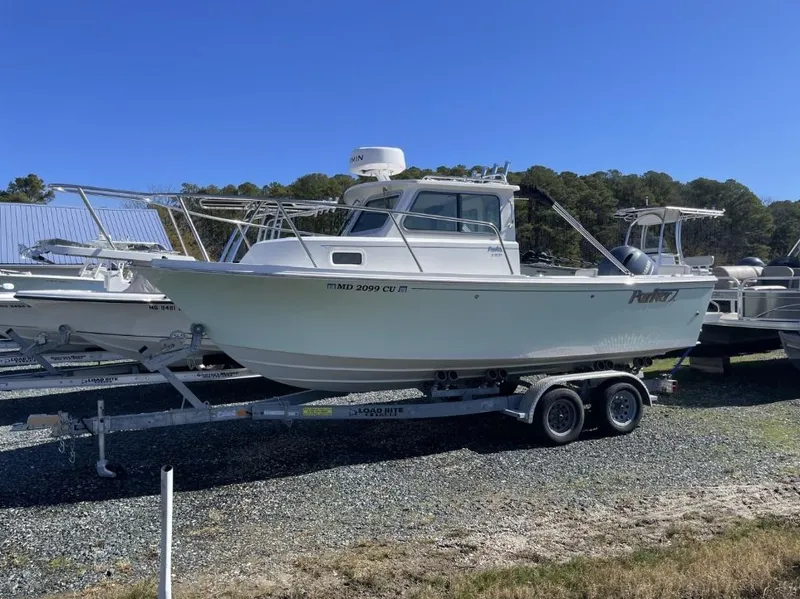 Slide: The Image of 2022 Parker 2120 boat on trailer, parked outdoors under clear blue sky. - 1
