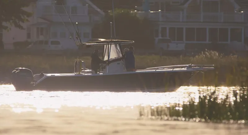 Slide: The Image of 2008 Pursuit C 250 Center Console boat on calm water at sunset near houses. - 1