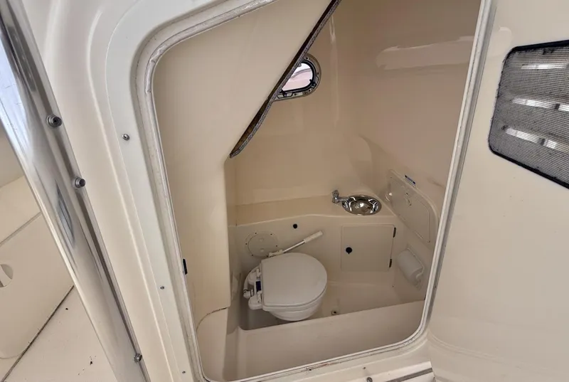 Slide: The Image of 2008 Pursuit C 250 Center Console boat interior with compact marine toilet and sink. - 15