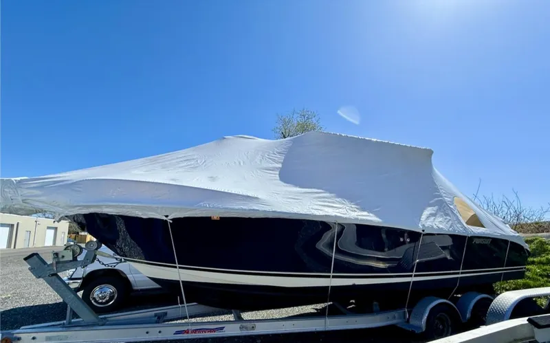 Slide: The Image of 2008 Pursuit C 250 Center Console boat covered on a trailer under clear blue sky. - 2