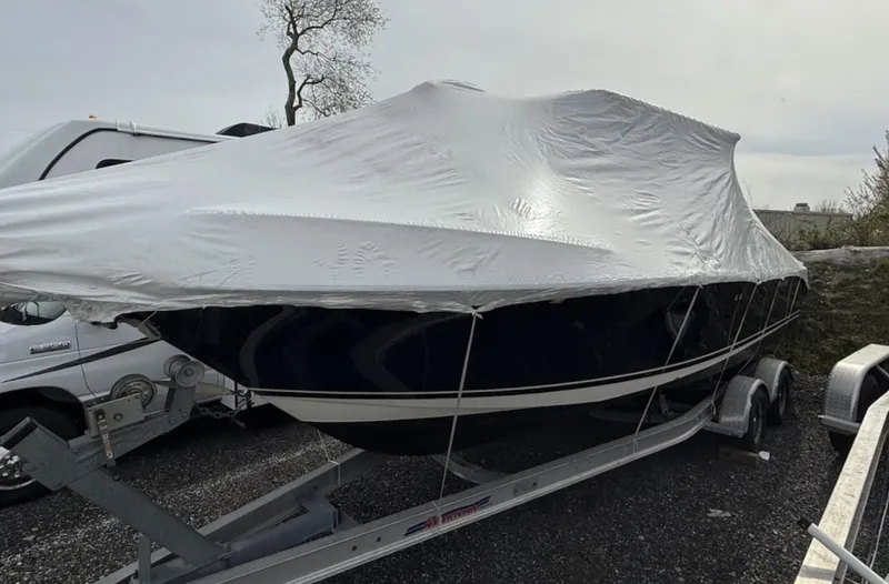 Slide: The Image of 2008 Pursuit C 250 Center Console boat covered on a trailer, parked outdoors. - 24