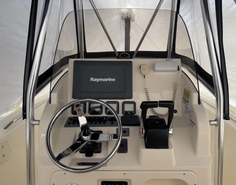 Slide: The Image of 2008 Pursuit C 250 Center Console boat dashboard with Raymarine display and steering wheel. - 9