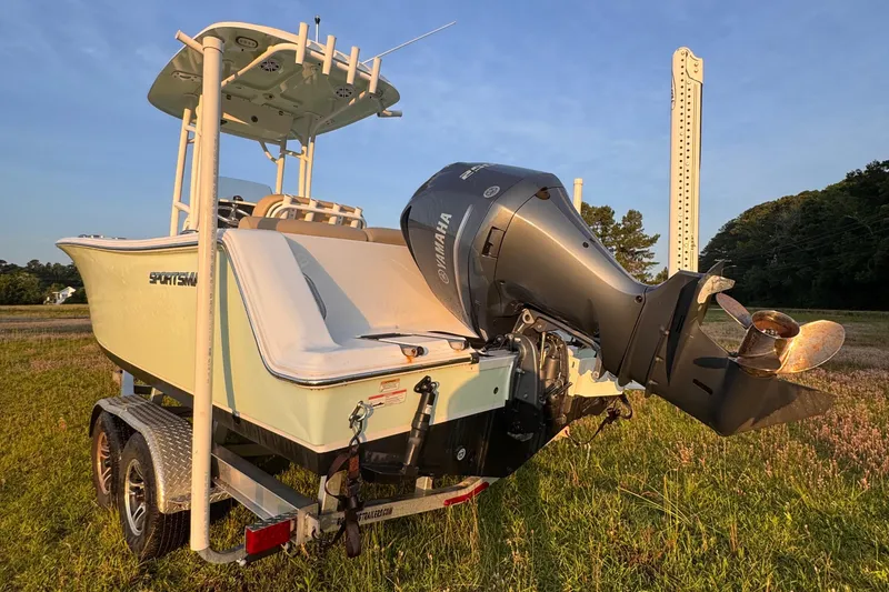 Slide: The Image of 2019 Sportsman 231 Heritage Platinum boat on trailer, featuring Yamaha outboard motor, in grassy field. - 5