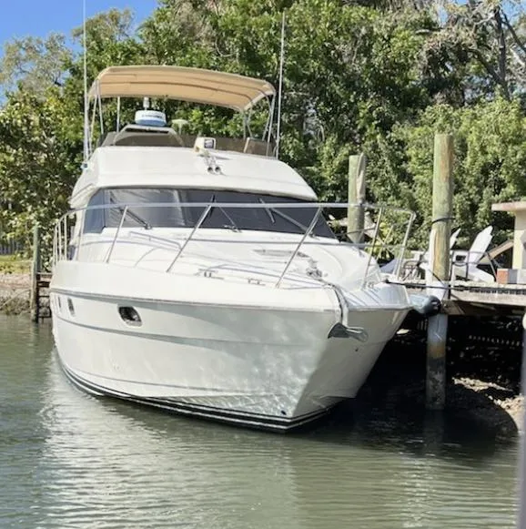 Slide: The Image of 1998 Viking Princess 46 Flybridge Sport Cruiser docked by lush greenery. - 3