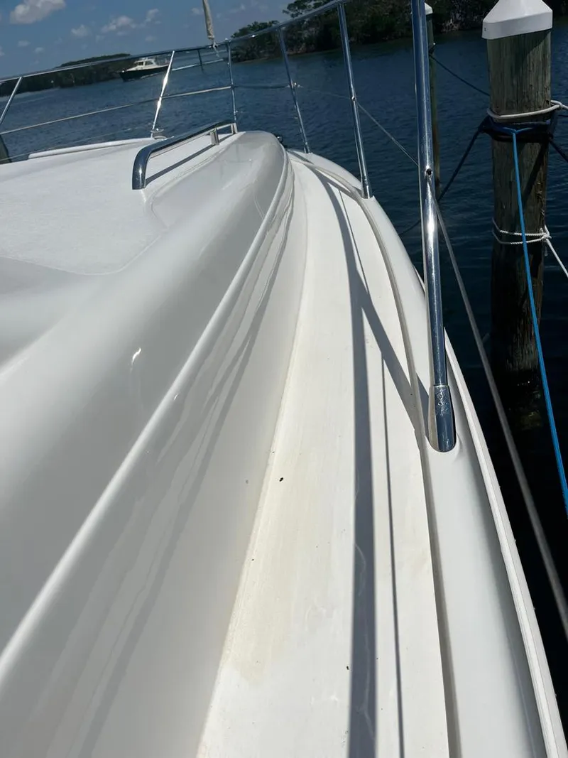 Slide: The Image of 1998 Viking Princess 46 Flybridge Sport Cruiser, sleek deck view by the water. - 7