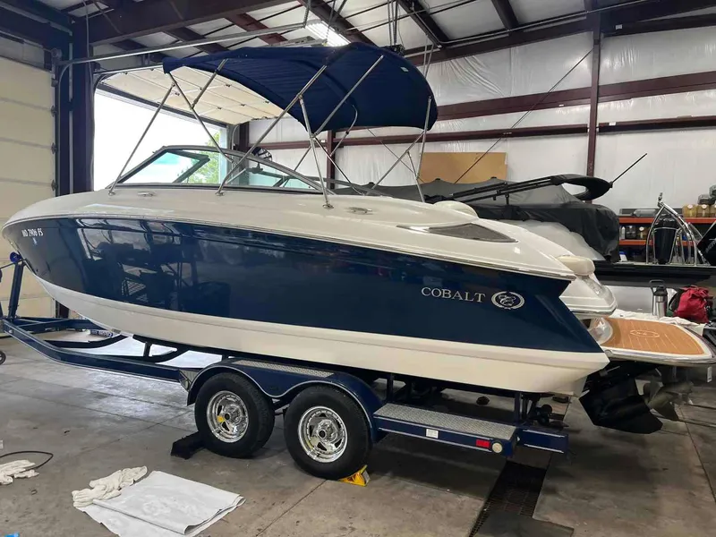 Slide: The Image of 2008 Cobalt 232 boat in a garage, blue and white exterior, on a trailer. - 1