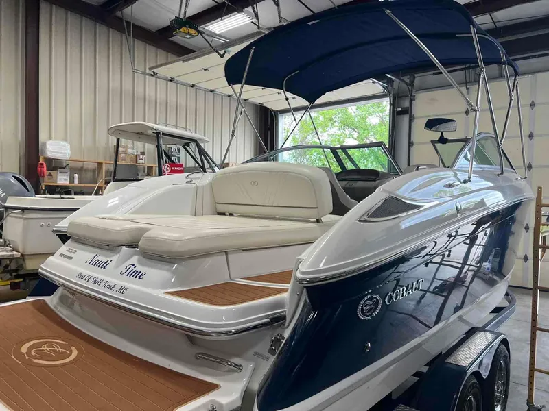Slide: The Image of 2008 Cobalt 232 boat with blue hull and white interior in a garage setting. - 5