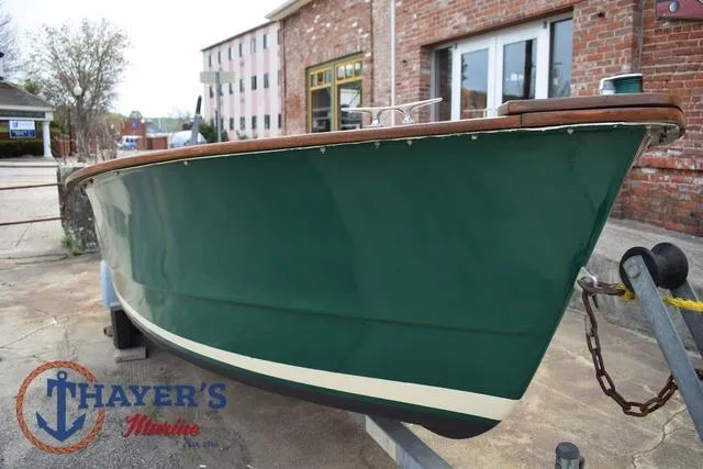 Slide: The Image of 1980 Carolina Skiff boat with green hull on trailer, parked near brick building. - 6