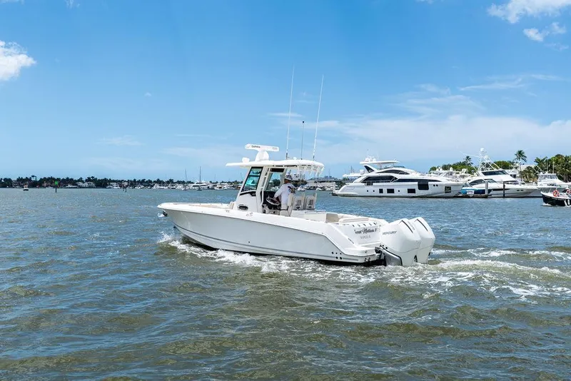 Slide: The Image of 2020 Boston Whaler 280 Outrage cruising on a sunny day with yachts in the background. - 11