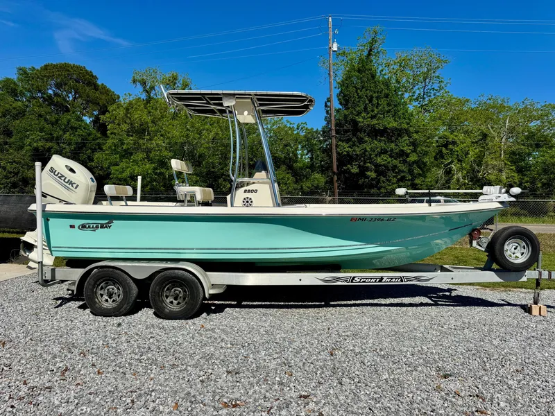 Slide: The Image of 2018 Bulls Bay 2200 boat on trailer, parked outdoors, with trees in the background. - 2