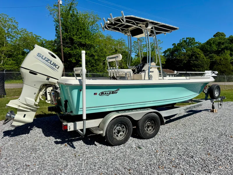 Slide: The Image of 2018 Bulls Bay 2200 boat on trailer with Suzuki outboard motor, parked on gravel. - 3
