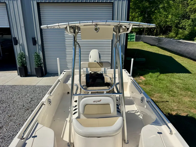 Slide: The Image of 2018 Bulls Bay 2200 boat with T-top, parked near a garage and grassy area. - 7