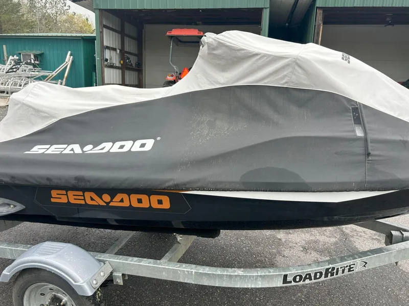 Slide: The Image of 2015 Sea-Doo GTX 155 covered on trailer, parked outside a green building. - 25