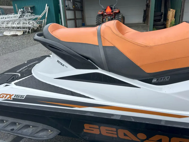 Slide: The Image of 2015 Sea-Doo GTX 155 jet ski with orange seat, parked near a garage. - 3