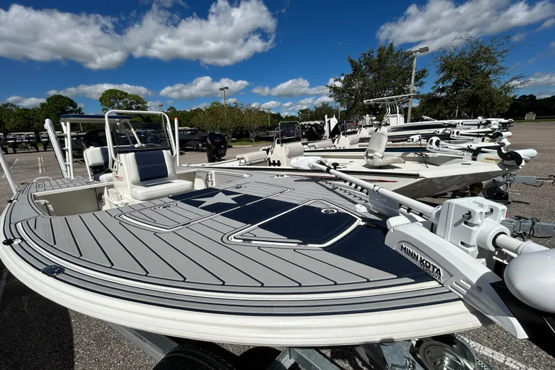 Slide: The Image of 2025 Mako 18 Pro Skiff Patriot Edition boat with Minn Kota trolling motor under a clear sky. - 2