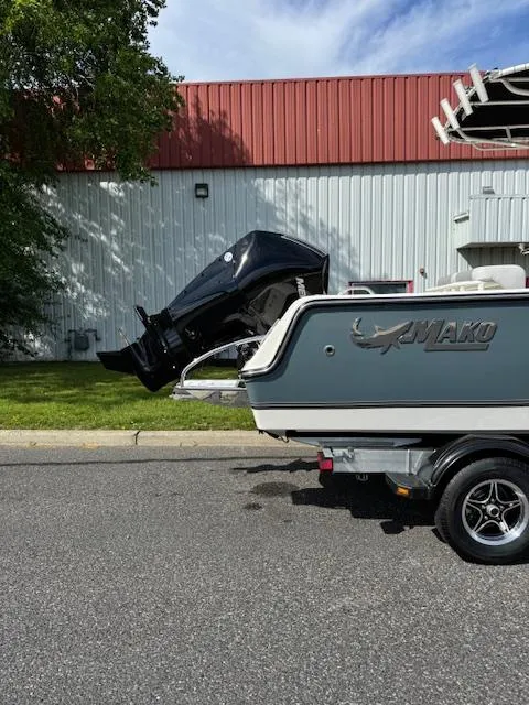 Slide: The Image of 2025 Mako 214 CC boat on trailer, parked outdoors, with visible outboard motor. - 2