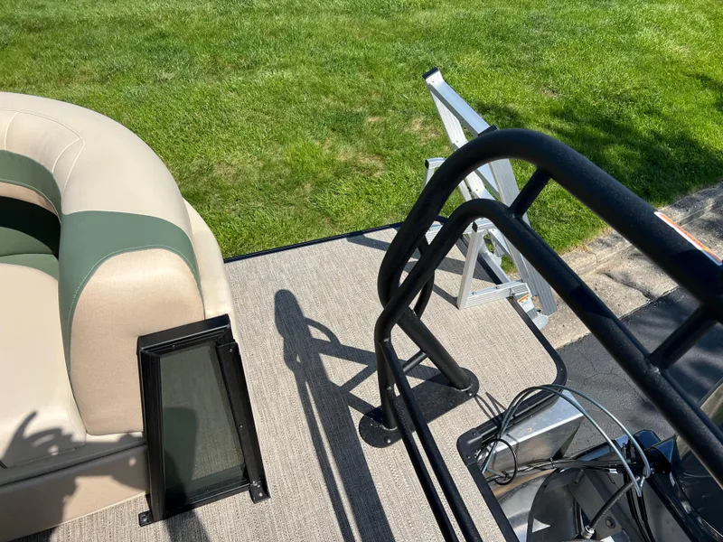 Slide: The Image of 2025 Godfrey Sweetwater 2286 Quad Social Tri-Toon deck with seating and railing, grassy background. - 17