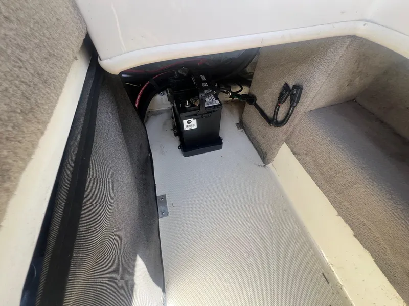 Slide: The Image of Battery compartment of a 2005 Sea Ray 220 Select boat, showing wiring and carpeted interior. - 22