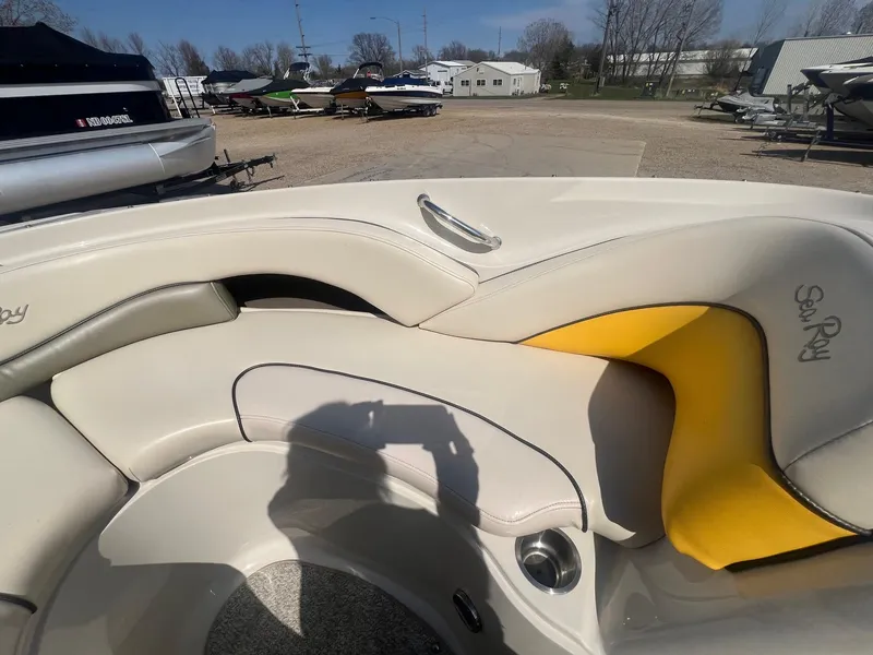 Slide: The Image of 2005 Sea Ray 220 Select boat interior with beige and yellow seating, parked outdoors. - 9